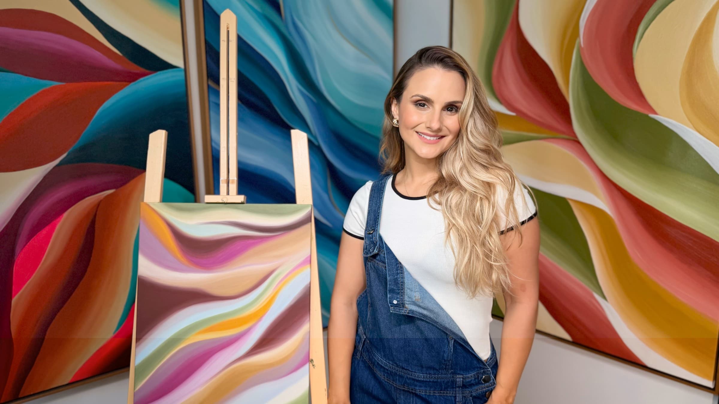 artista ao lado de suas pinturas